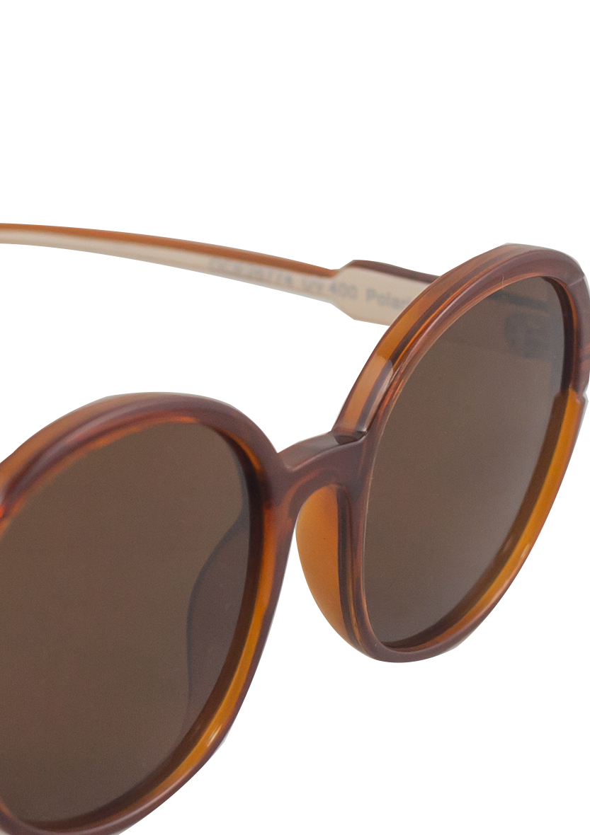 Close-up of Oceanides Brisa Crystal Brown Beige Sunglasses, featuring oversized round frames in a brown tortoiseshell design with dark tinted lenses, inspired by classic 80s style, set against a plain white background.