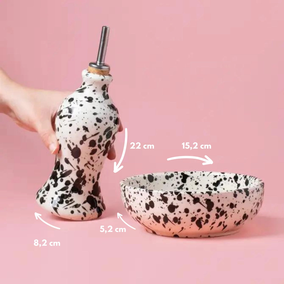 A hand holds the Alfar Tierra Cocida GALAXY Breakfast Grater and Oil Pourer Kit (pourer: 22cm tall, 8.2cm base; bowl: 15.2cm diameter, 5.2cm tall)—a perfect kitchen gift—on a pink background with measurement arrows shown.