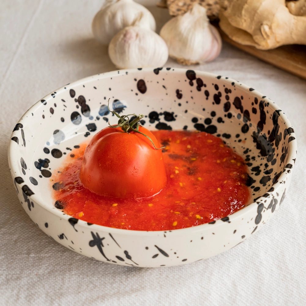 A whole tomato rests in red sauce with garlic and ginger nearby—ideal inspiration for gifting the Alfar Tierra Cocida GALAXY Breakfast Grater and Oil Pourer Kit, beautifully displayed on a light tablecloth.