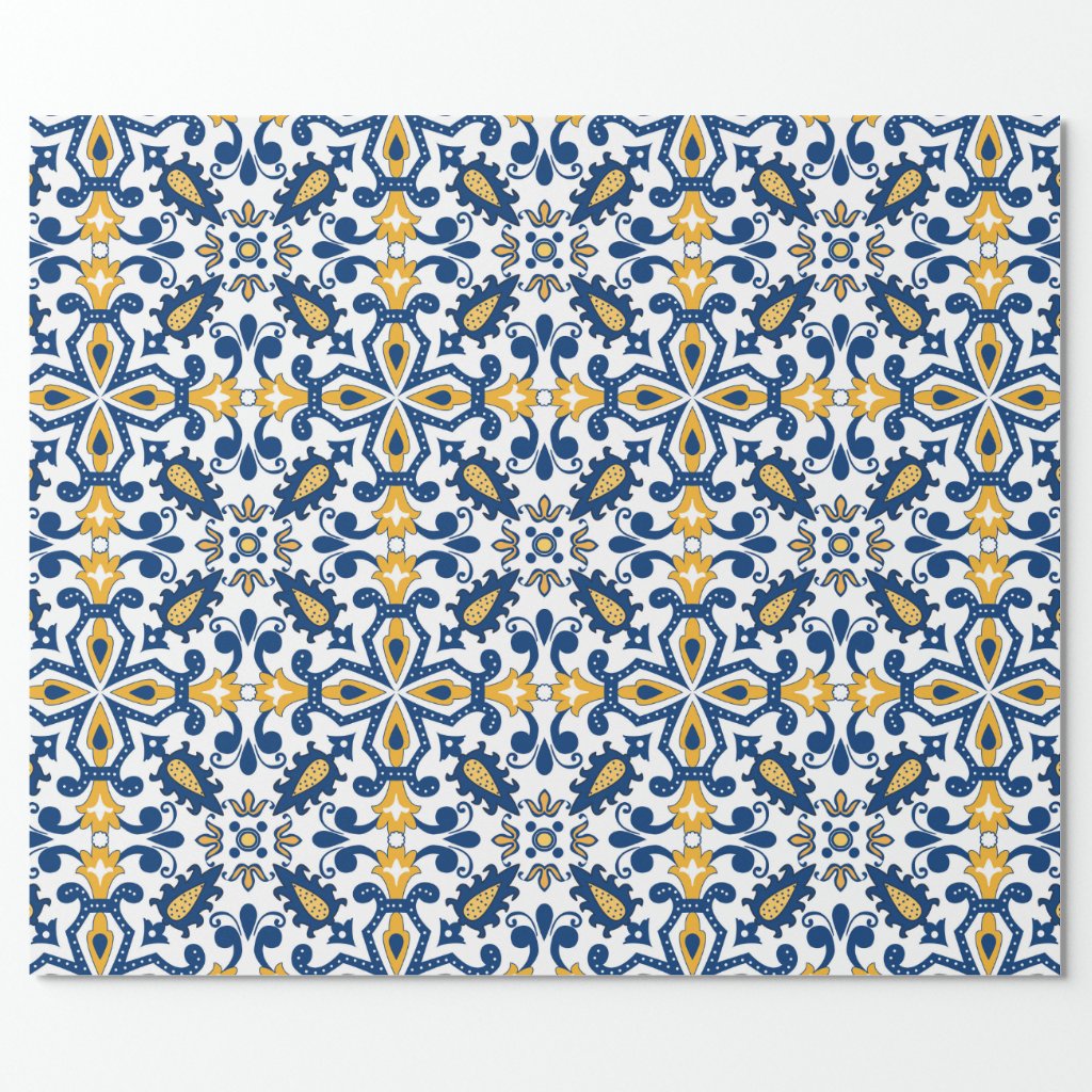Wrapped Gift Wrapping features a rectangular fabric with a blue, yellow, and white geometric-floral pattern inspired by Mediterranean tiles. Its slightly wavy edges stand out against a plain background, making it ideal for unique gift presentations.