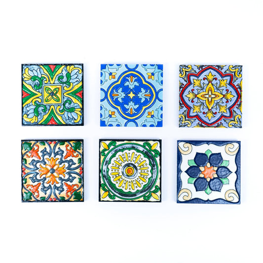 The Meninas Bonitas Cork Tile-Inspired Ceramic & Cork Coasters Set of 6 features vibrant geometric and floral designs in blue, green, yellow, orange, and red, artistically arranged on six beautiful coasters.
