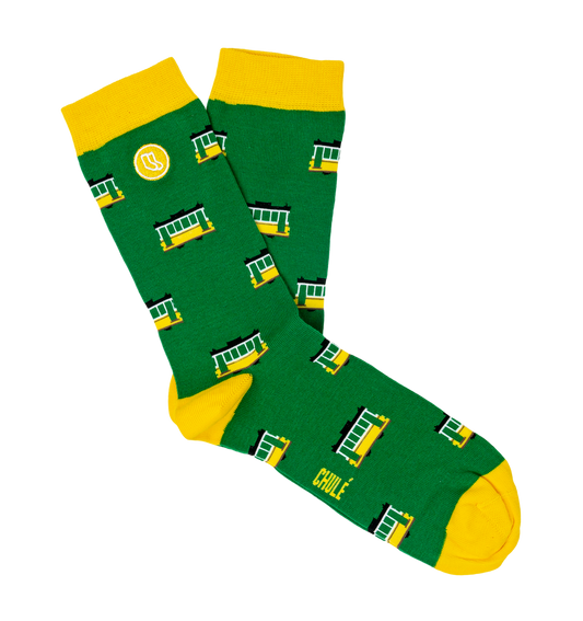 Green socks with yellow toes, heels, and cuffs, decorated with cheerful streetcars and a small logo, are included in the Lisbon Essentials Box by Iberica—Pretty things from Portugal. CHULE is printed near the toe, making them a unique Lisbon-inspired gift.