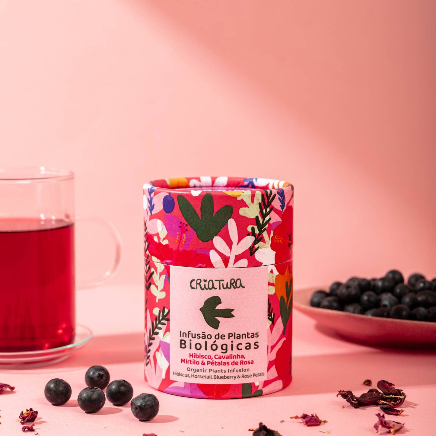 Pink tea caddy with blueberry and rose petals on a table