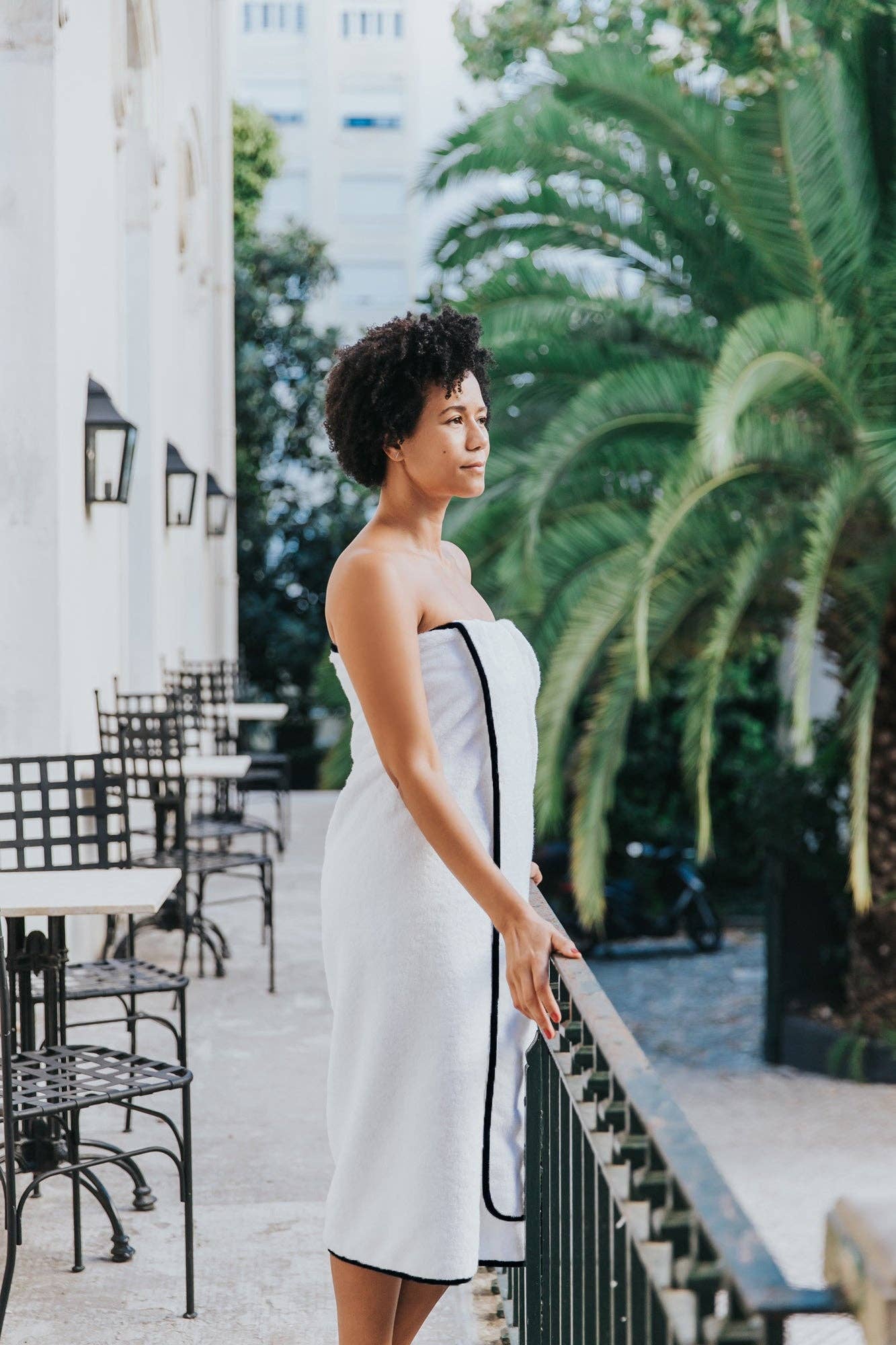 woman wearing a black mira bath towel looking over a balcony