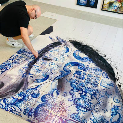 Person working on a large blue and white ceramic tile design.