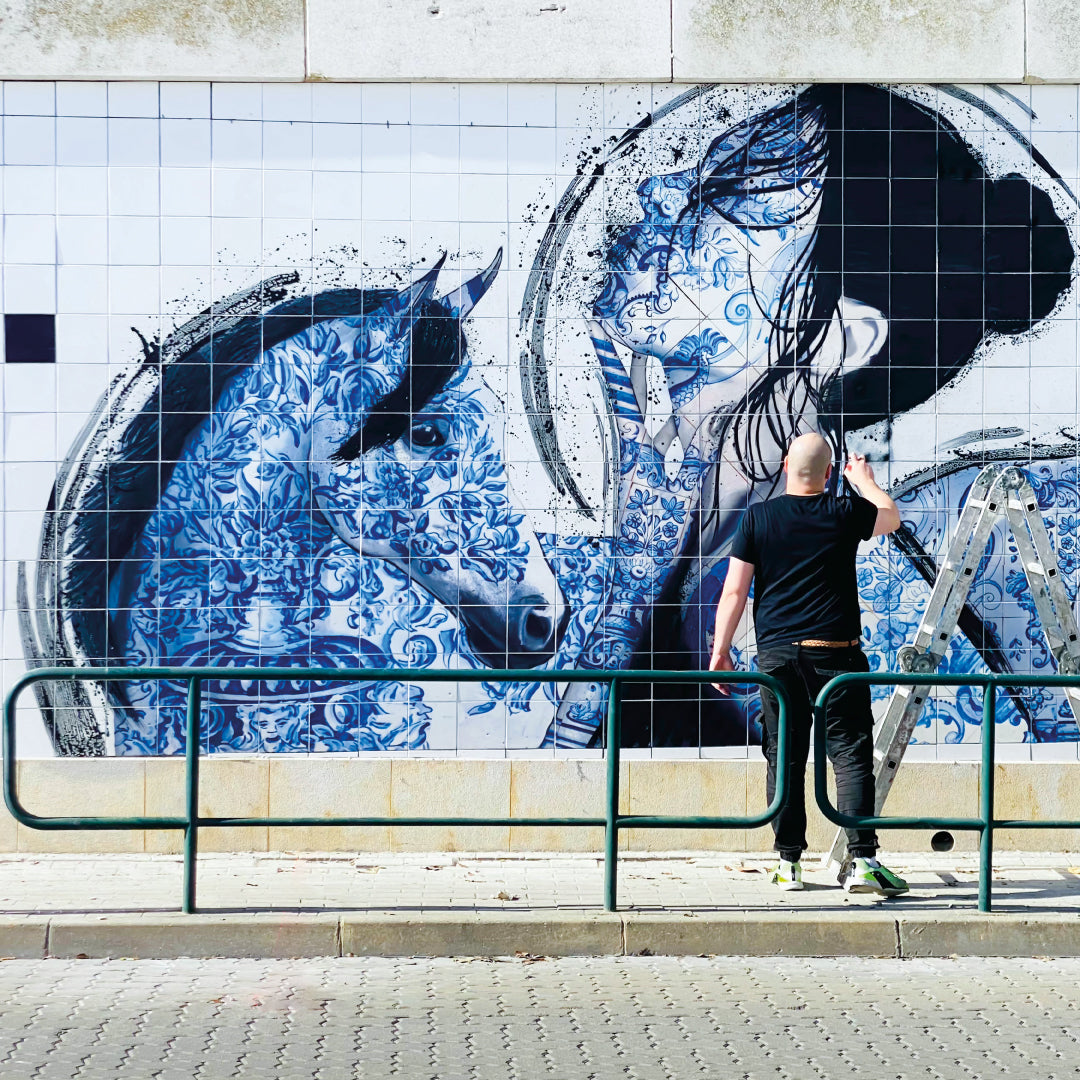 Person painting a large mural of a horse on a wall.