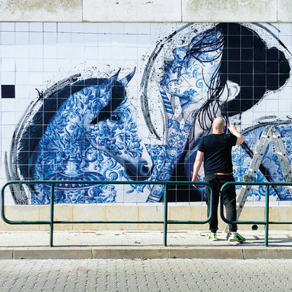 Person painting a large mural of a horse on a wall.
