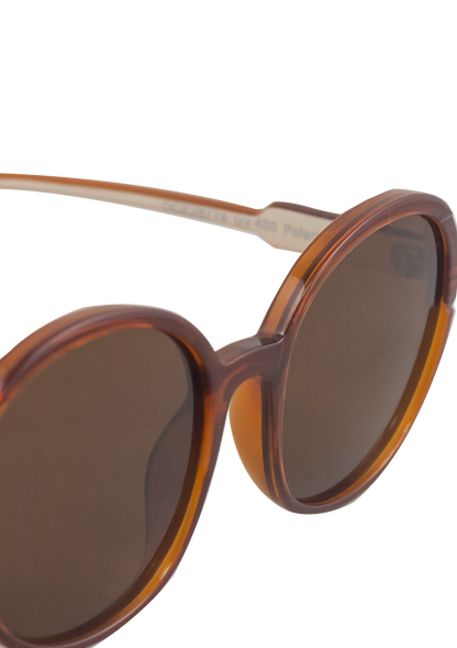 Close-up of Oceanides Brisa Crystal Brown Beige Sunglasses, featuring oversized round frames in a brown tortoiseshell design with dark tinted lenses, inspired by classic 80s style, set against a plain white background.