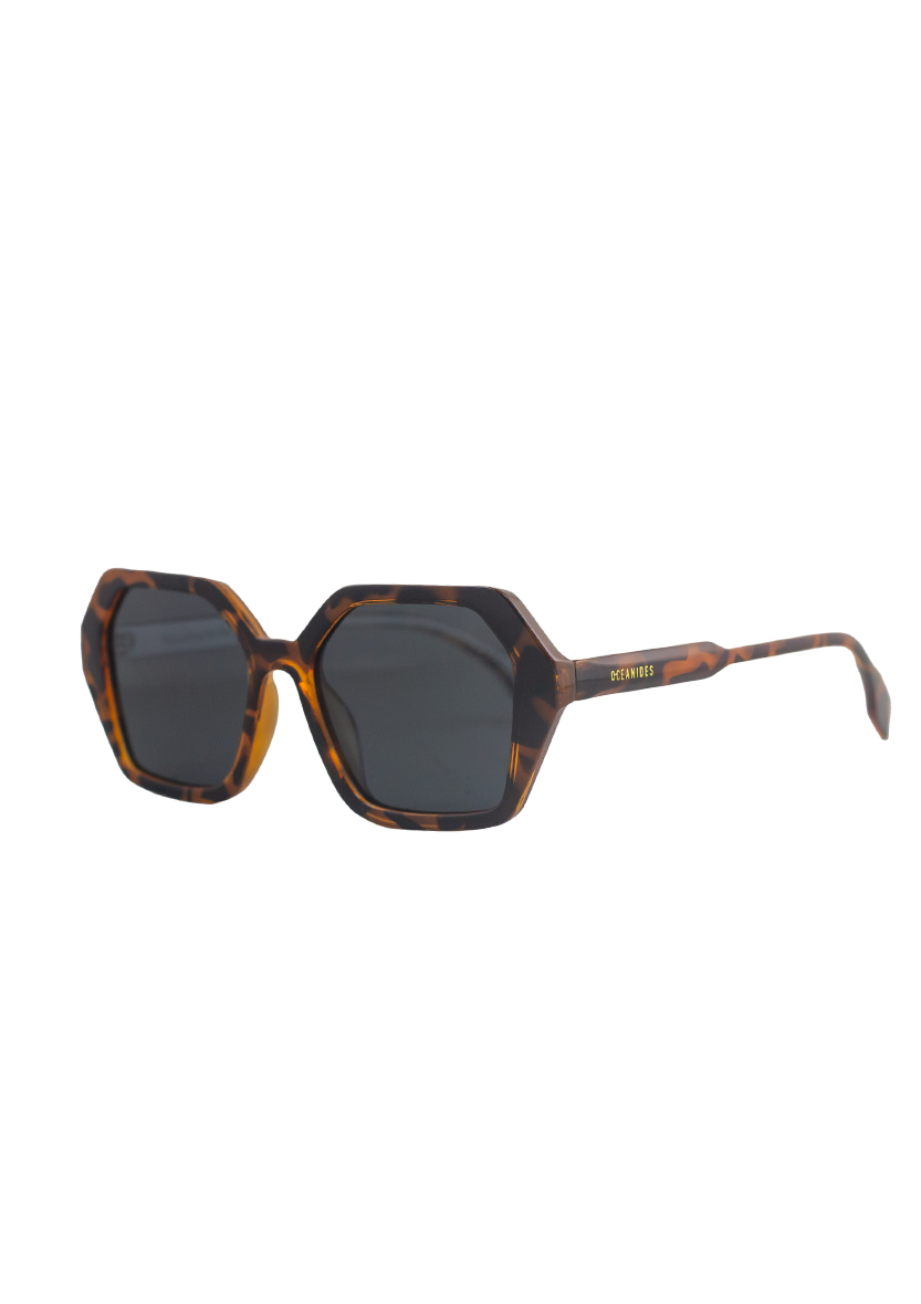 Coral Dark Havana Sunglasses by Oceanides feature thick, angular tortoiseshell frames with polarized lenses. A small gold Oceanides logo accents the temple arm. Shown photographed on a white background.