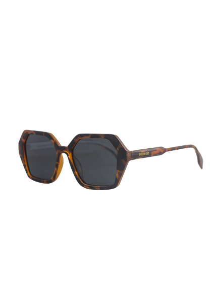 Coral Dark Havana Sunglasses by Oceanides feature thick, angular tortoiseshell frames with polarized lenses. A small gold Oceanides logo accents the temple arm. Shown photographed on a white background.