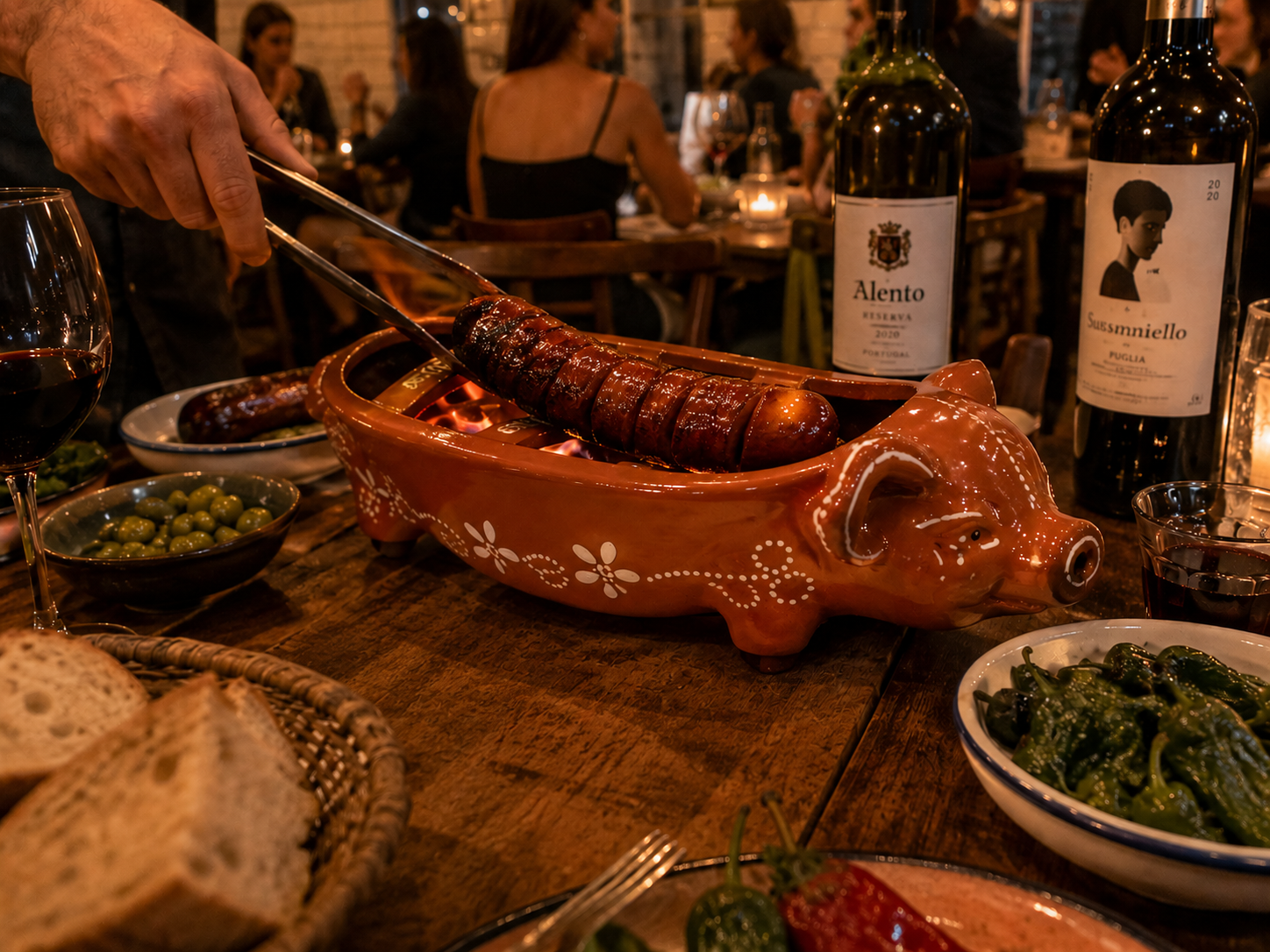 Traditional Portuguese ceramic pig grill serving flaming chorizo sausage tableside in a warm Iberian-inspired restaurant with rustic décor.