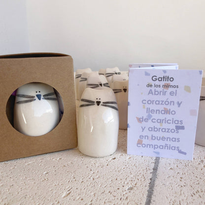 The Kitten Amulet of Cuddles by Picuru ceramicas is a handmade ceramic cat figurine in a brown box with window, accompanied by a Spanish card—an ideal friendship or comfort gift to inspire hugs and good company.