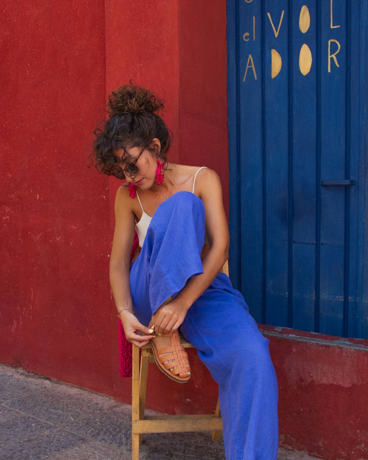 lady in blue trousers tying up her camel sandals