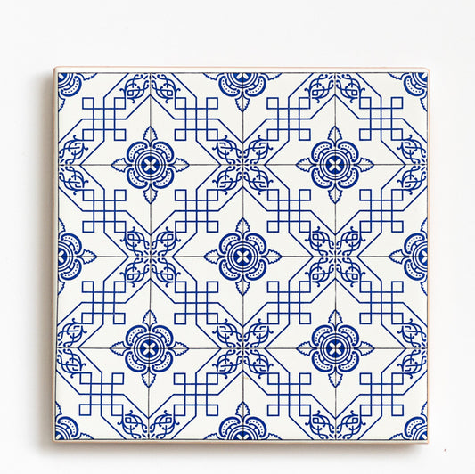 The Ceramic drinks coaster 11cm - Azulejo 24 by ObjectoAnonimo features a blue and white geometric pattern with floral motifs and diamond shapes, echoing traditional Portuguese tile design. Ideal for use as a decorative azulejo coaster.