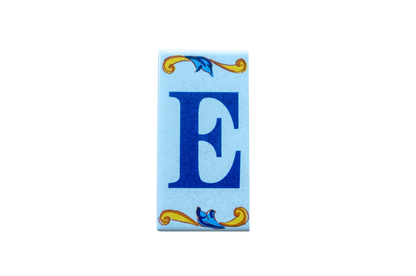Lisa Croquets Letters – Ceramic House Letter Tiles rectangular tile featuring a large dark blue E centered between decorative blue and gold scrollwork accents on a light blue background.