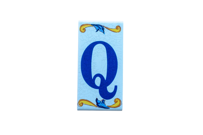 Lisa Croquets Letters – Ceramic House Letter Tile featuring a blue letter Q on a light blue background with decorative yellow and blue scrollwork at the top and bottom.